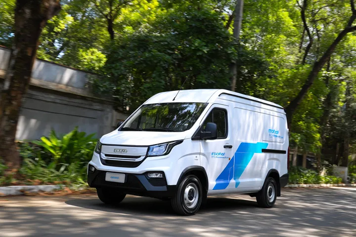 Van de entrega elétrica em movimento por uma rua arborizada